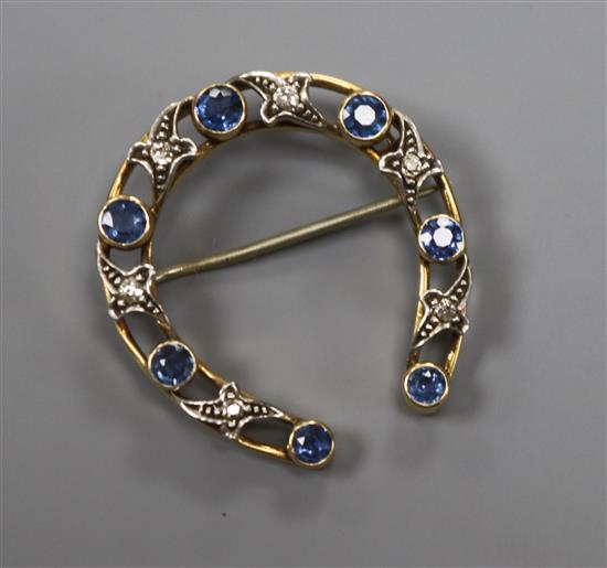 A yellow metal, sapphire and diamond horseshoe brooch, 30mm.